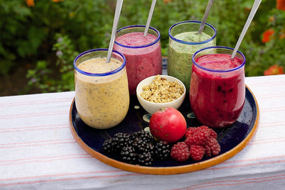 A plate displaying four colorful smoothies in various flavors, arranged attractively for presentation.