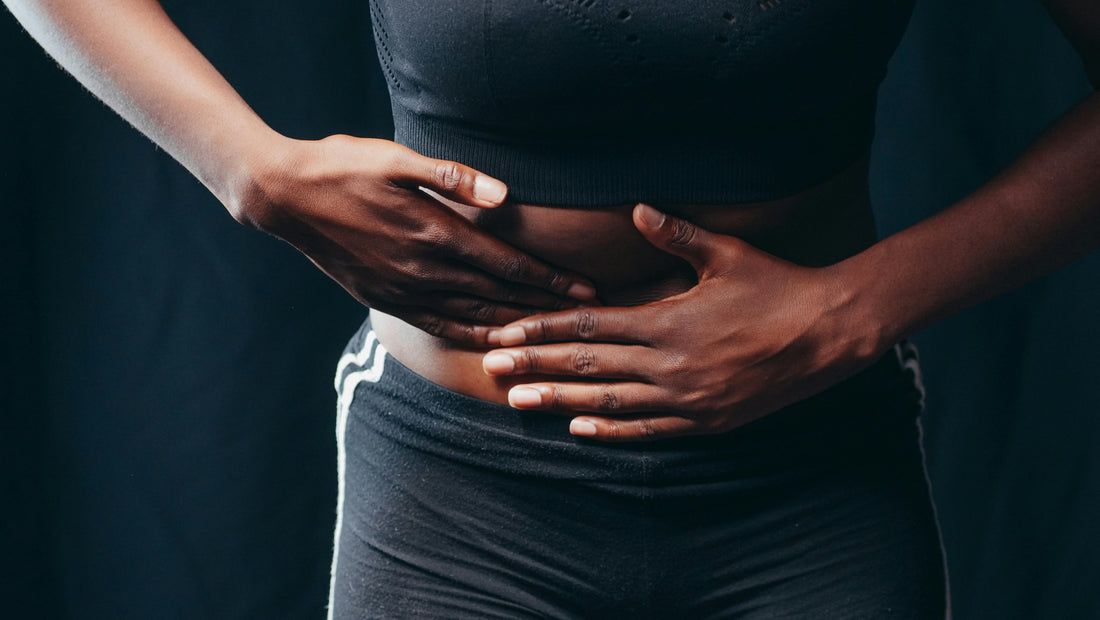 A woman stands with her hands gently resting on her stomach, conveying a sense of calm and contemplation.